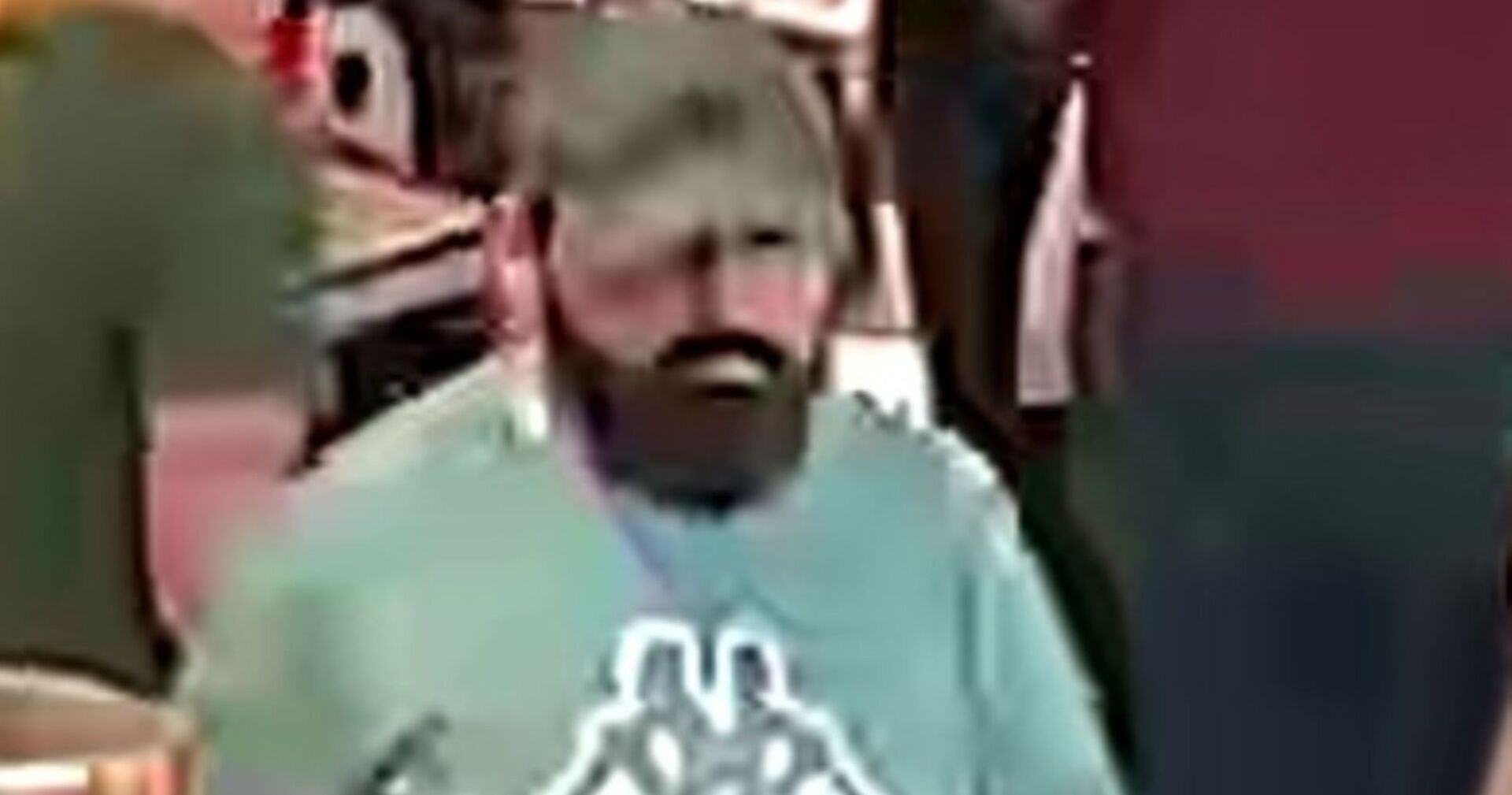 Mann mit dunklem Vollbart, dunkelgrüner Kappe und hellgrünem Shirt