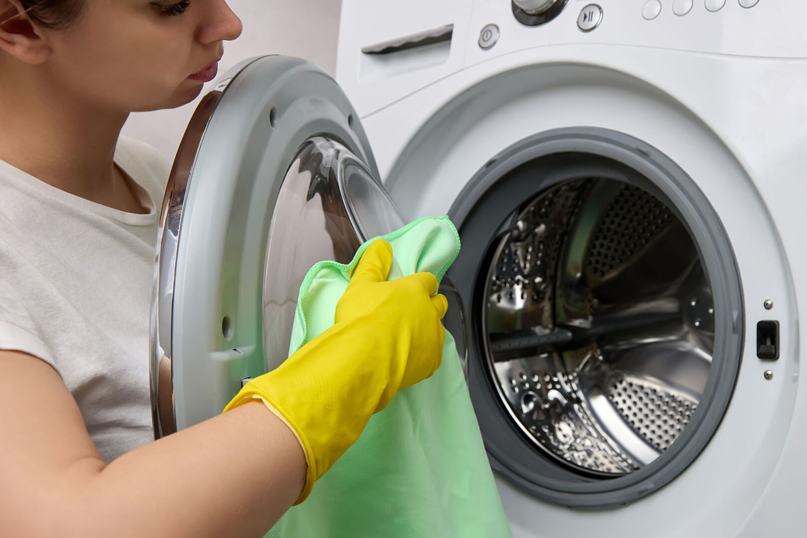 Frau reinigt Waschmaschinentür | Credit: iStock.com/Aleksandr Zyablitskiy