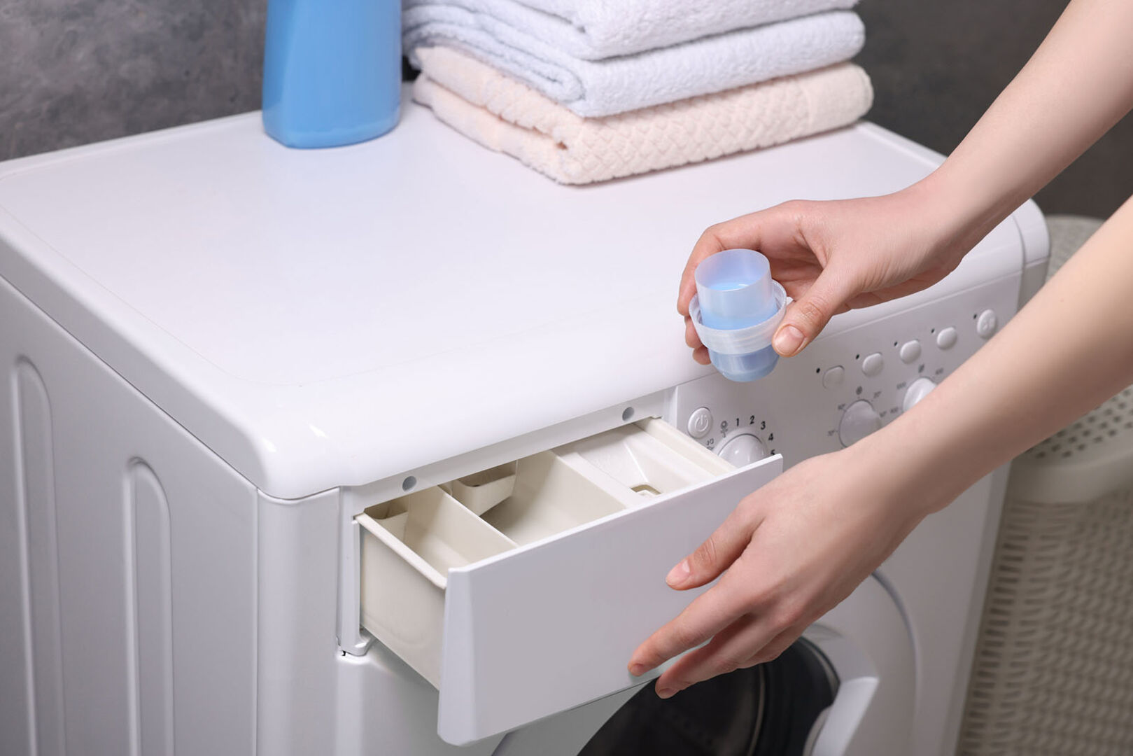 Frau gibt Waschmittel in die Waschmaschine | Credit: iStock.com/Liudmila Chernetska