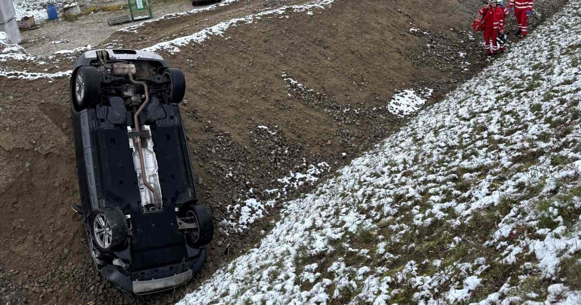Das Unfallauto auf dem Dach liegend im Straßengraben.