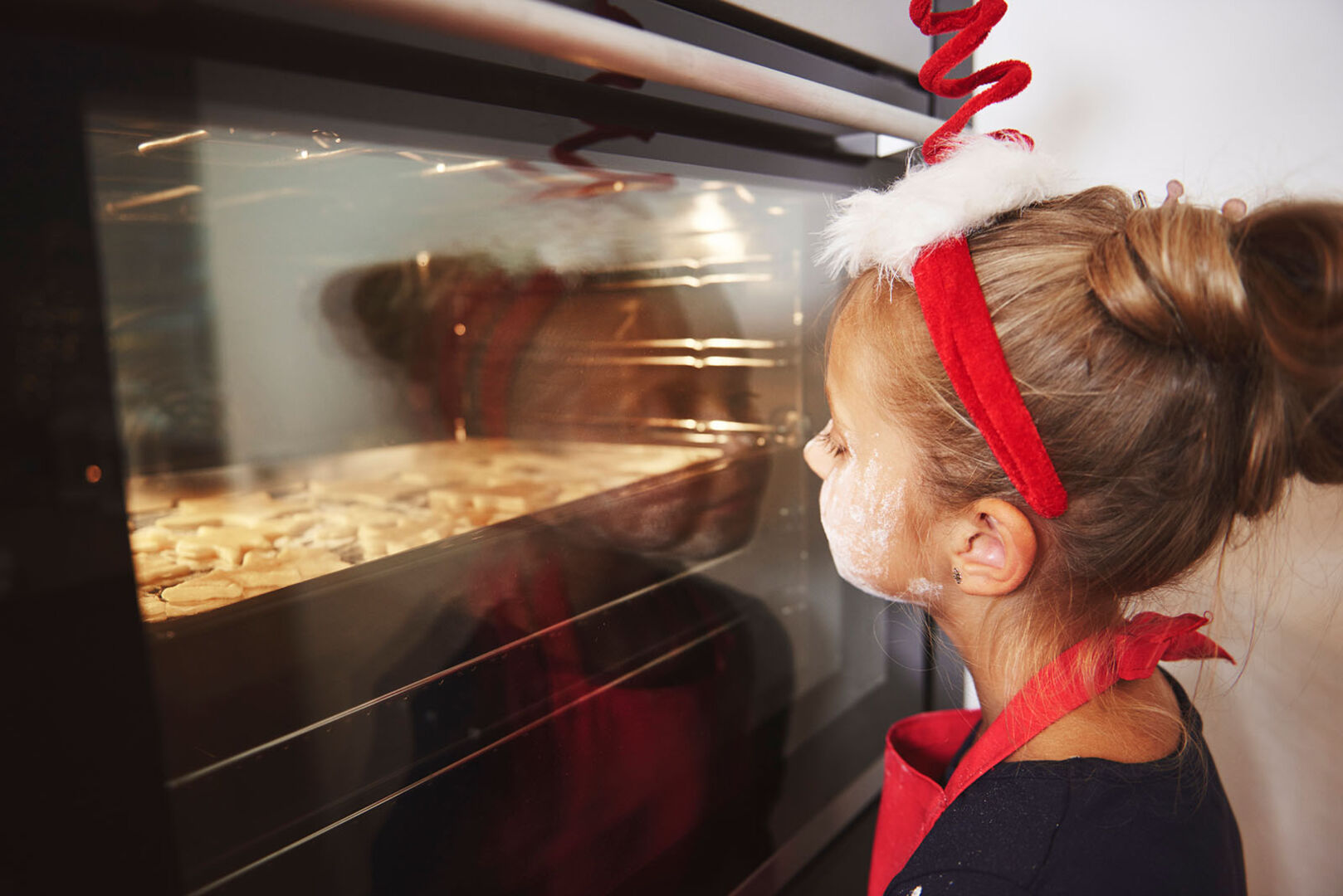 Mädchen sitzt vor Backofen | Credit: iStock.com/gpointstudio