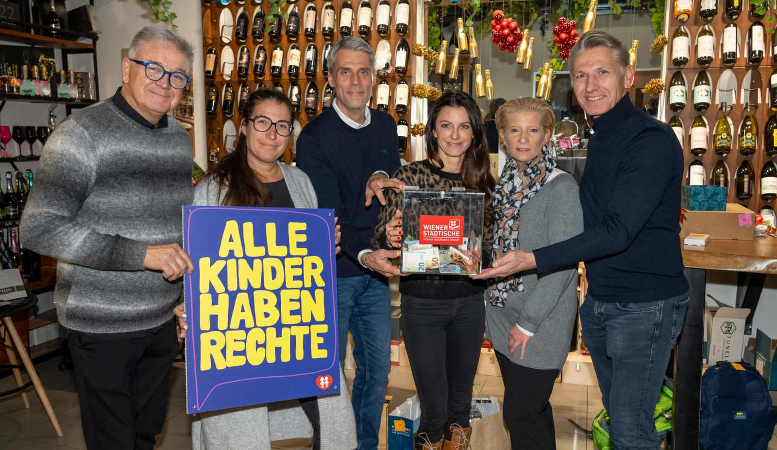 Mehrere Menschen halten ein Plakat und eine Spendenkiste