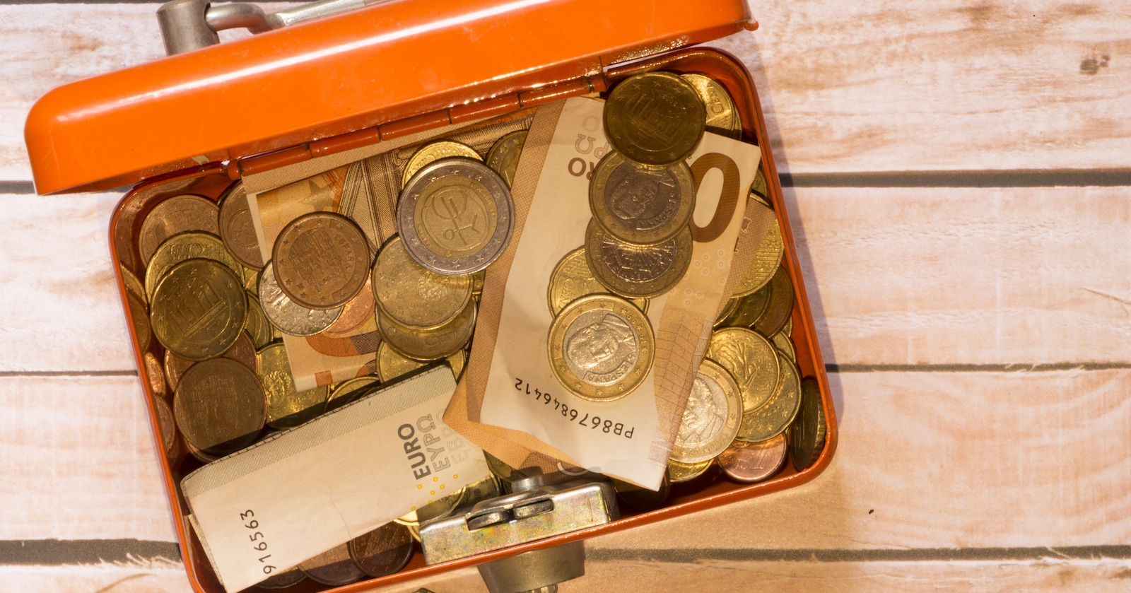 Euro-Scheine und -Münzen in einer orangen Dose.