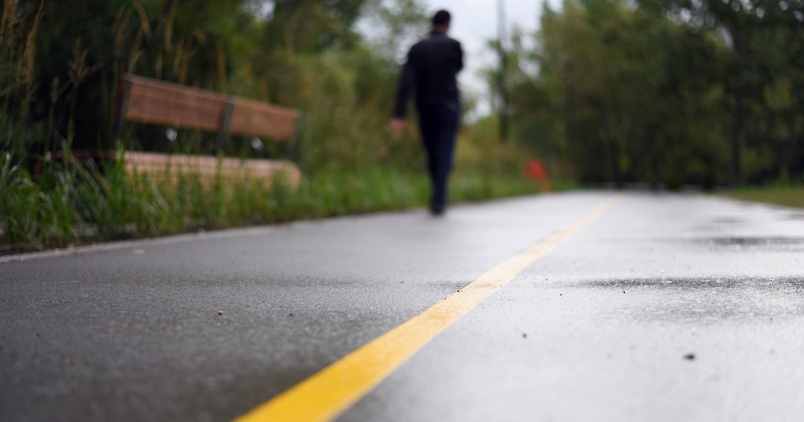 Ein schwarz gekleideter, nicht erkennbarer Mensch geht eine Straße entlang.