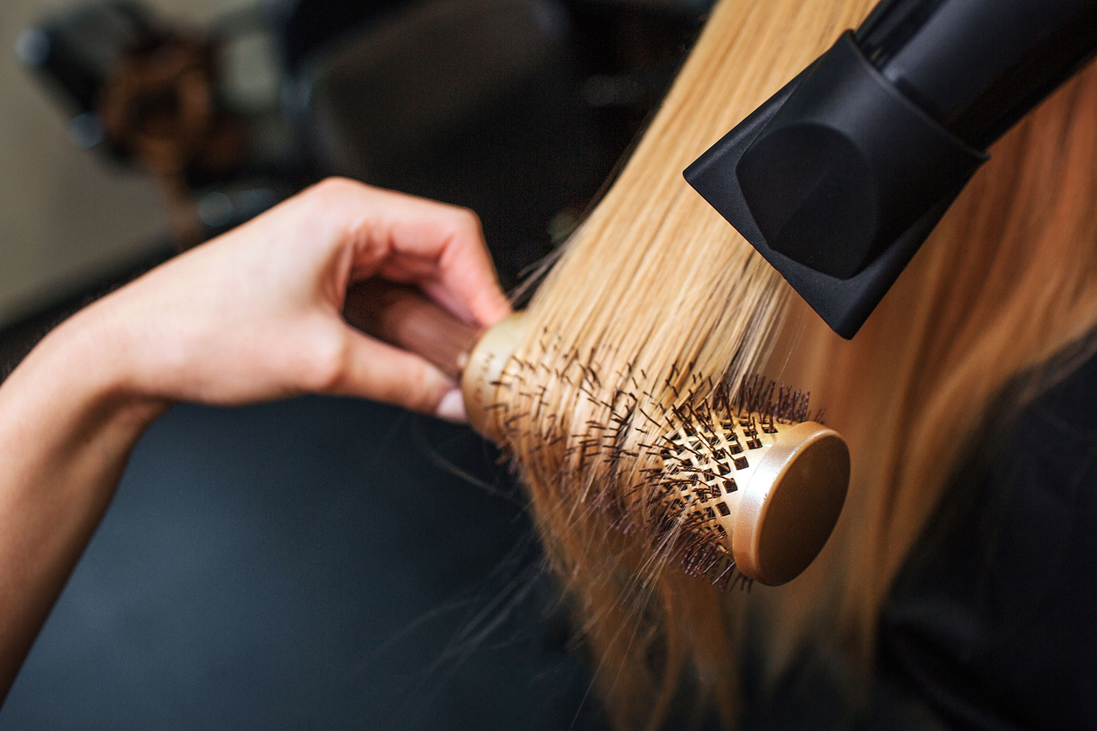 Friseurin fönt einer Kundin die Haare mit einer Rundbürste aus | Credit: iStock.com/Estradaanton