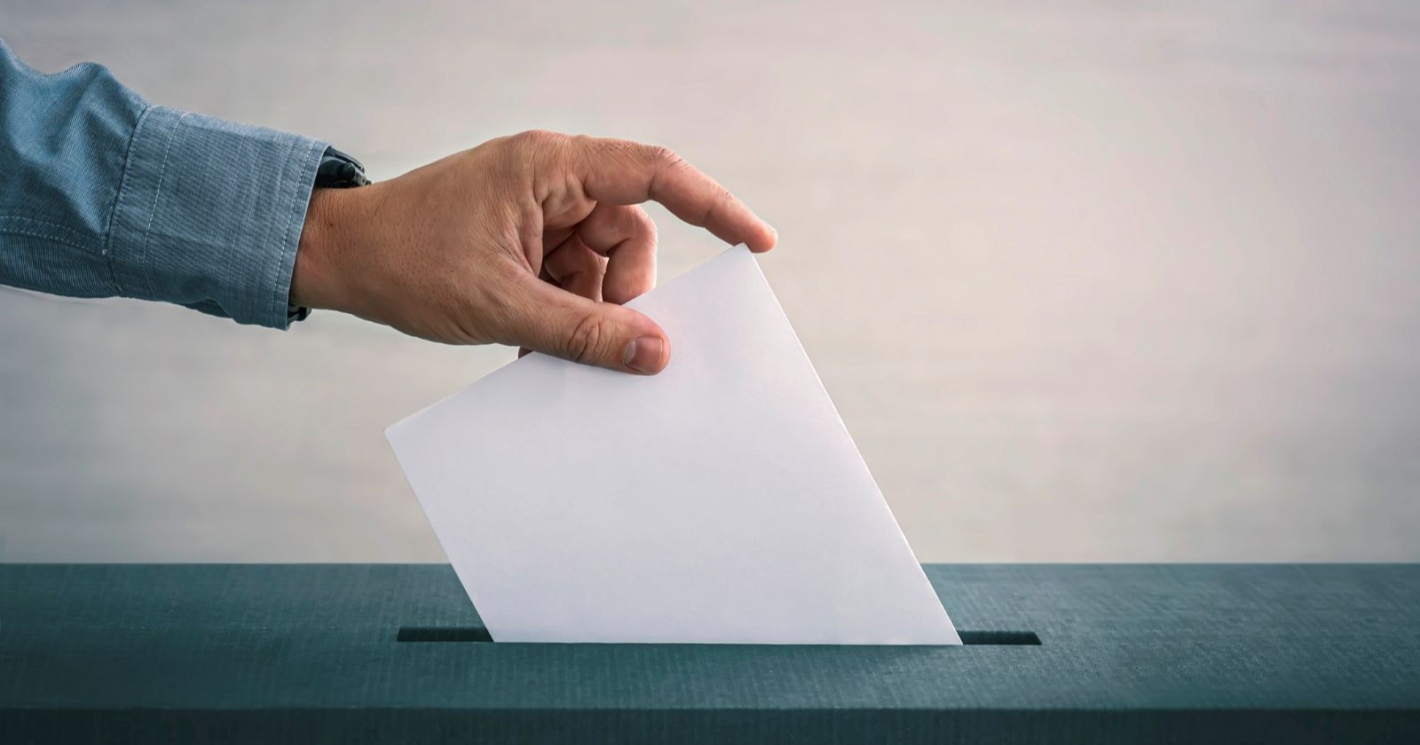 Mann wirft Stimmzettel in eine Box ein