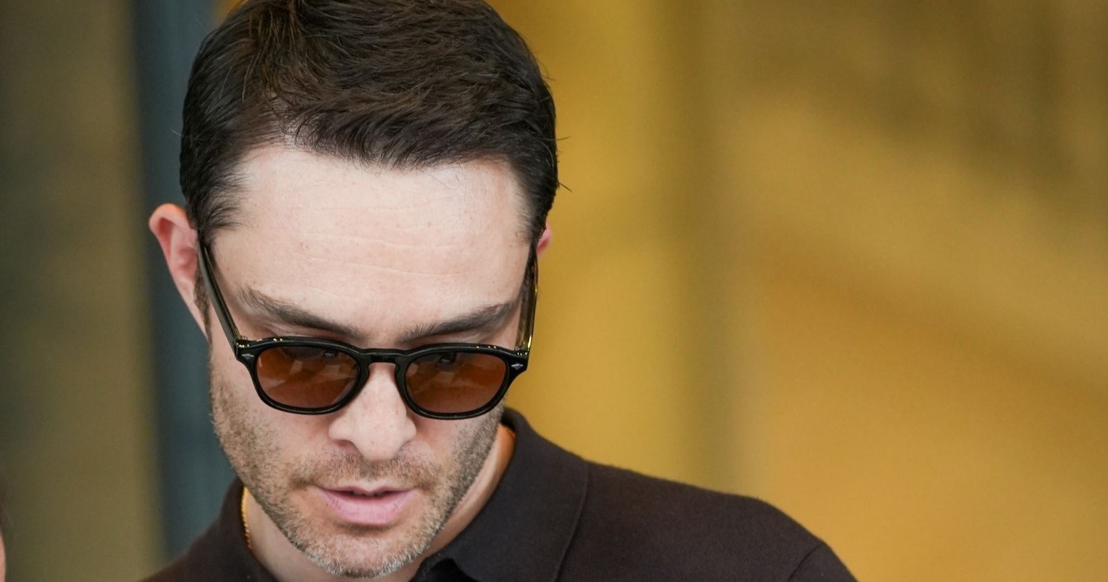 Ed Westwick trägt eine Sonnenbrille und schaut zu Boden