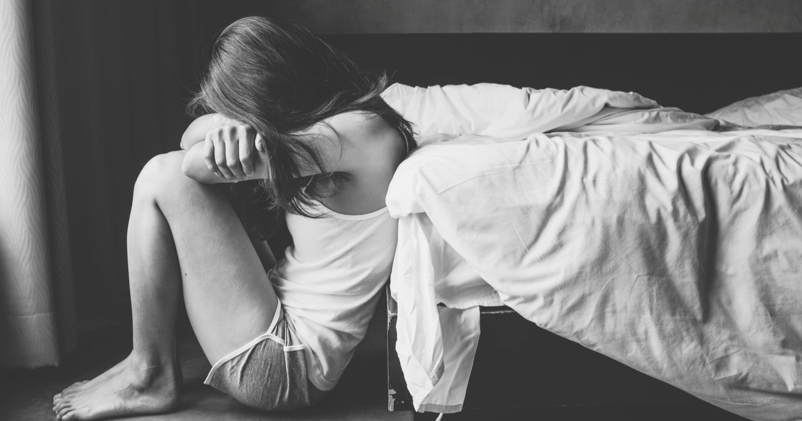 Mädchen welches gehockt o einem Bett sitzt