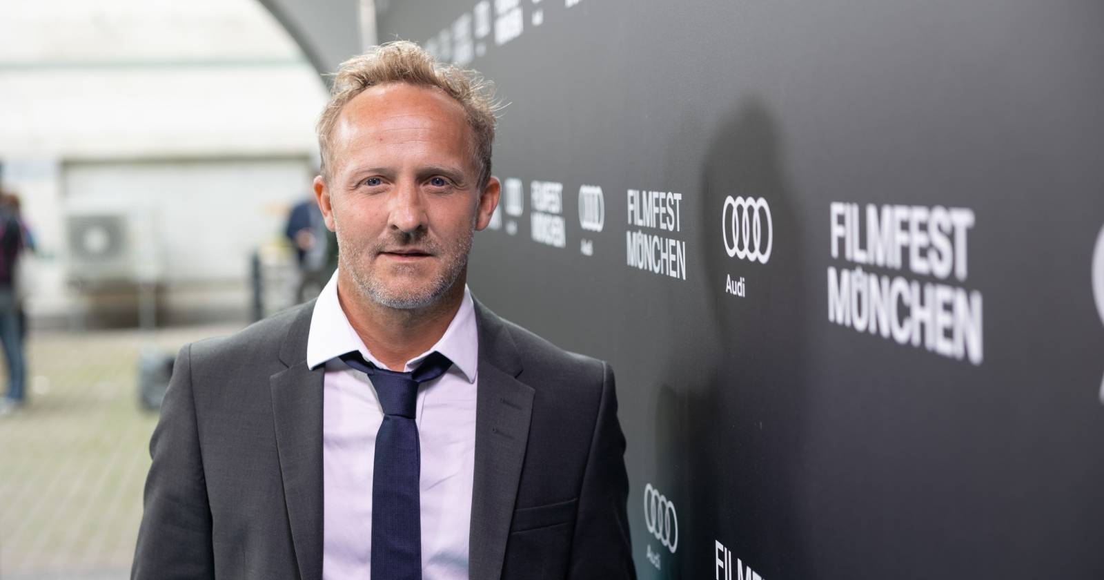 Bild des Schauspielers Maximilian Brückner, der einen Anzug mit Hemd und Krawatte trägt