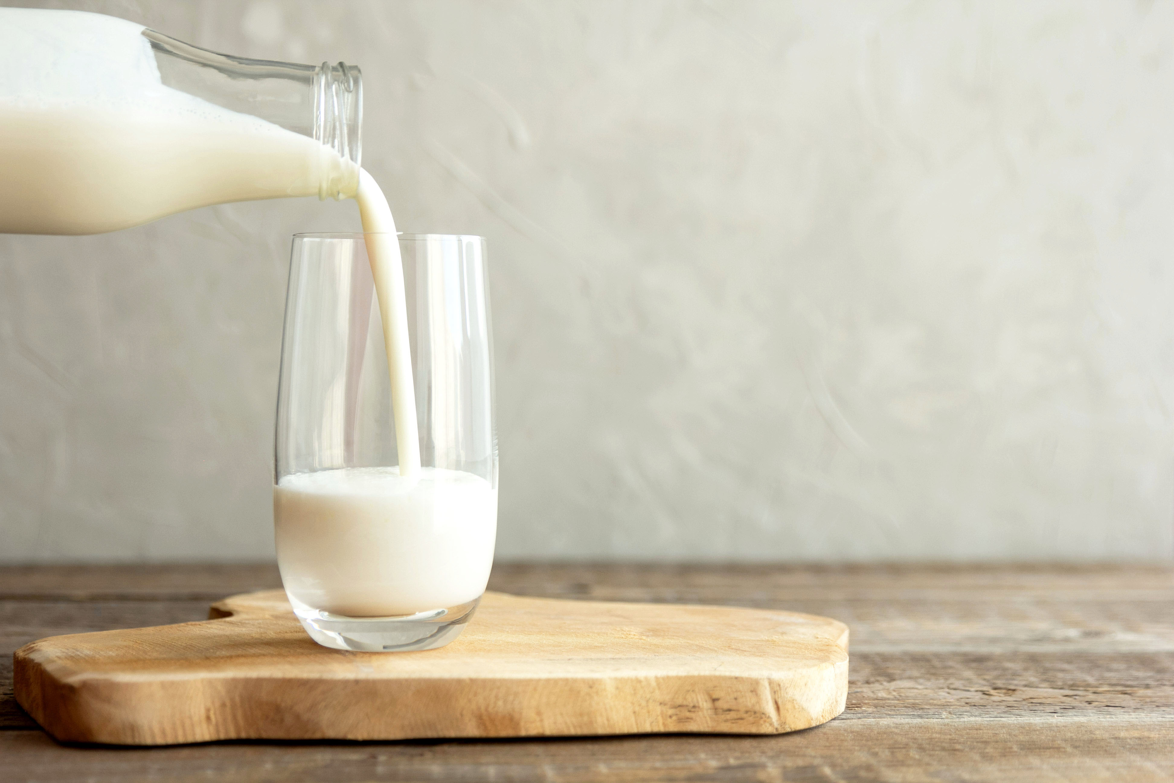Ein Glas, in das aus einer Flasche Milch gegossen wird