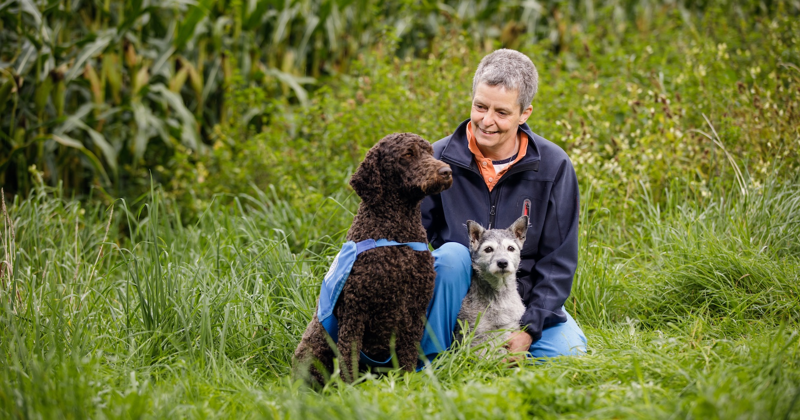 Gründerin Elisabeth Färbinger mit zwei ihrer Hund auf einer grünen Wiese.
