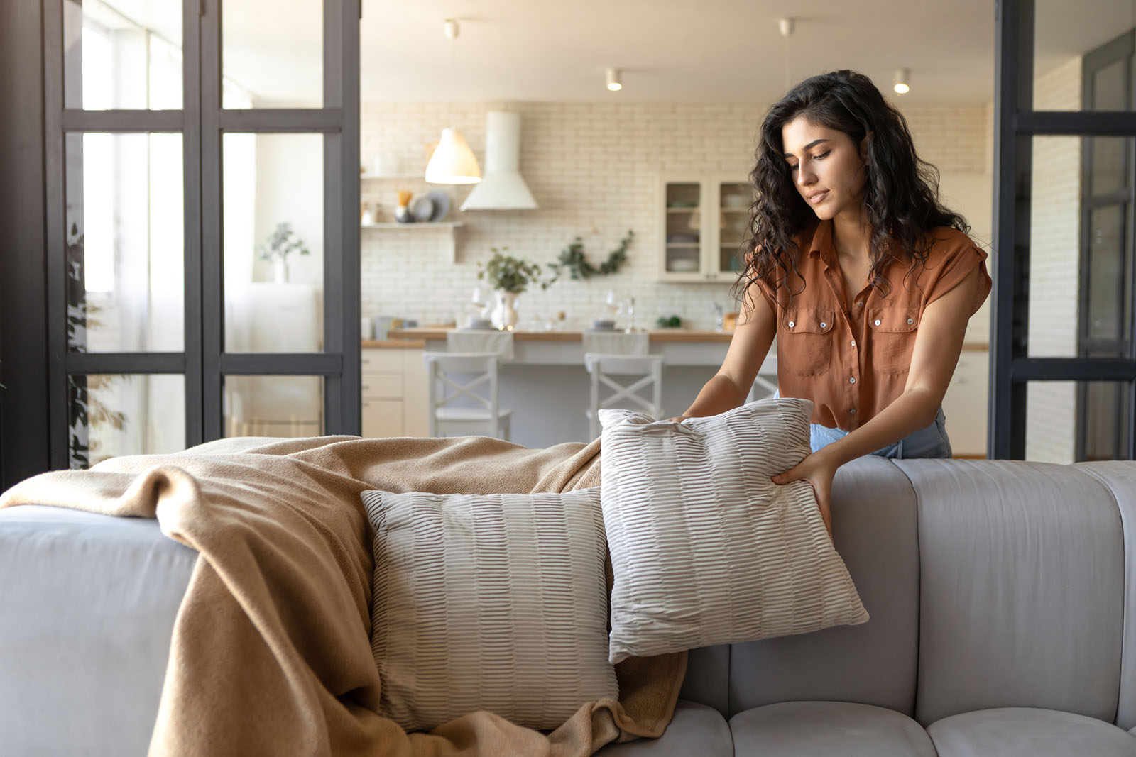 Frau dekoriert Sofa | Credit: iStock.com/Prostock-Studio