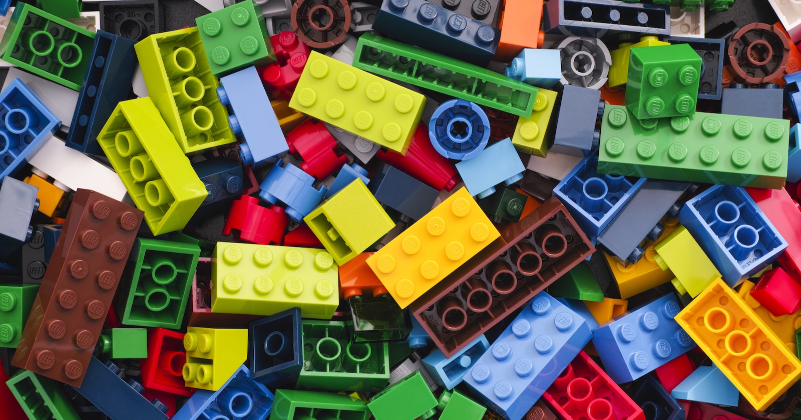 Bunte Sammlung verschiedener LEGO-Steine in unterschiedlichen Farben und Größen, chaotisch übereinander gestapelt.