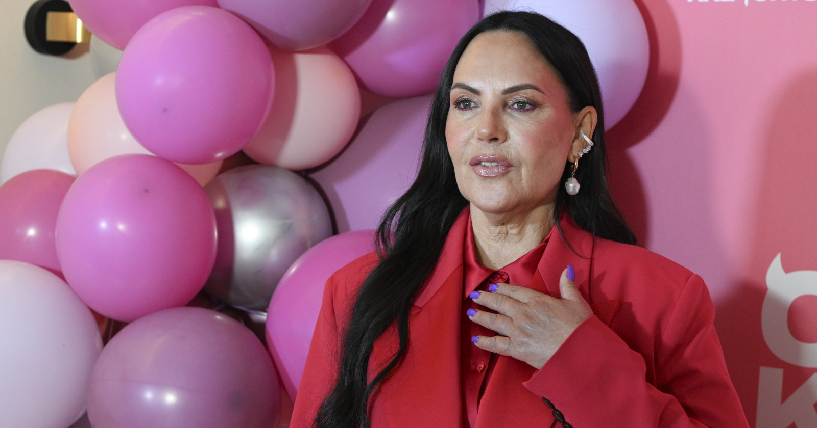 Frau mit dunklen Haaren trägt einen roten Anzug