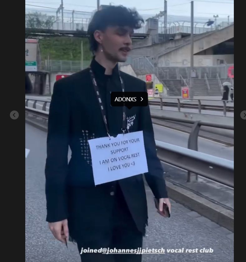 Adam Pavlovčin geht durch die Straßen von Basel mit einem Schild mit der Aufschrift, dass er seine Stimme schont. Er ist schwarz gekleidet