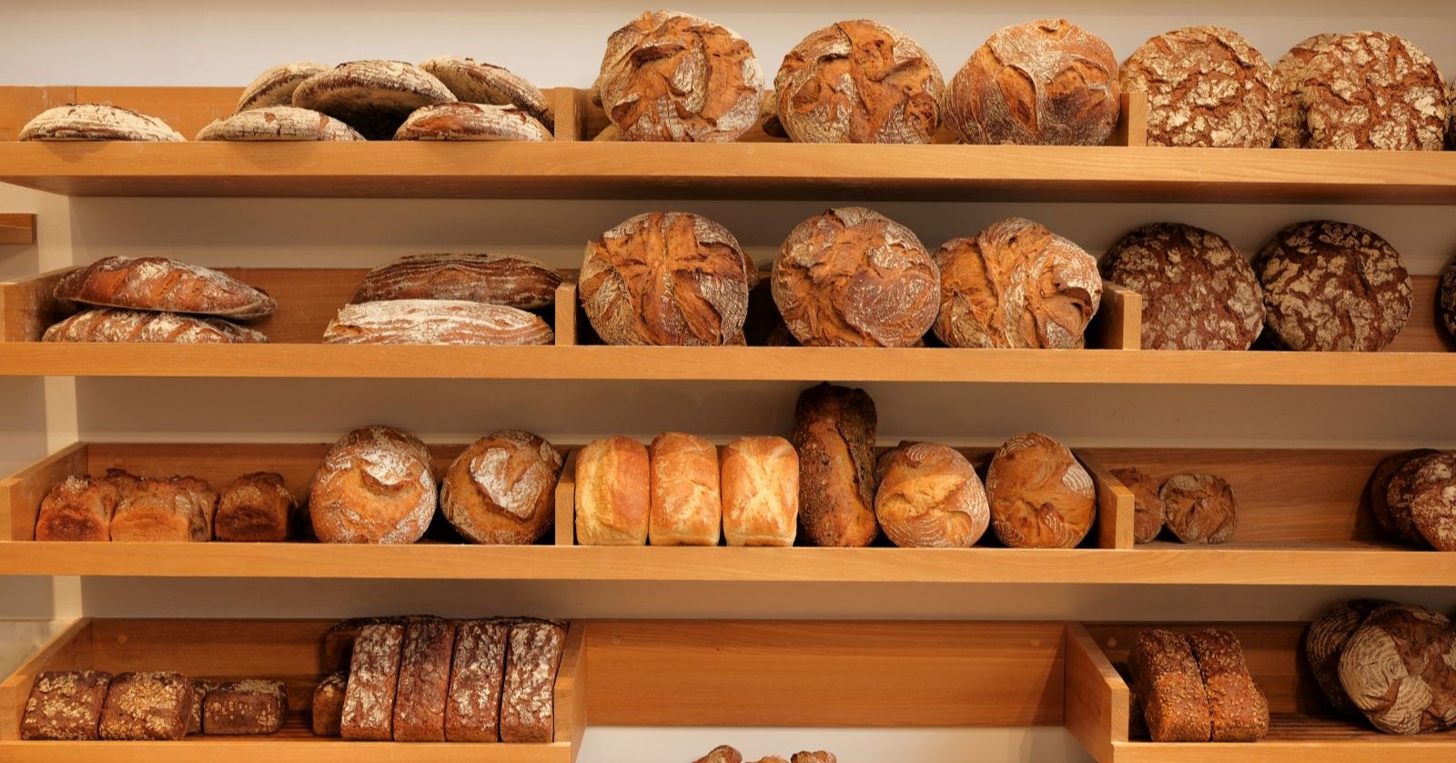 Verschiedene Brotsorten in einer Bäckerei auf Holzregalen präsentiert – symbolisch für das Sortiment der Bäckerei Moshammer aus Böhlwerk