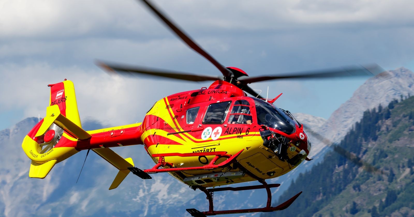 Rot-gelber Rettungshelikopter in den Bergen