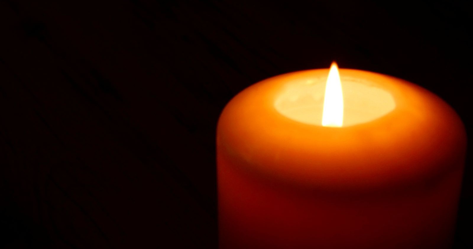 Rote Kerze brennt, schwarzer Hintergrund