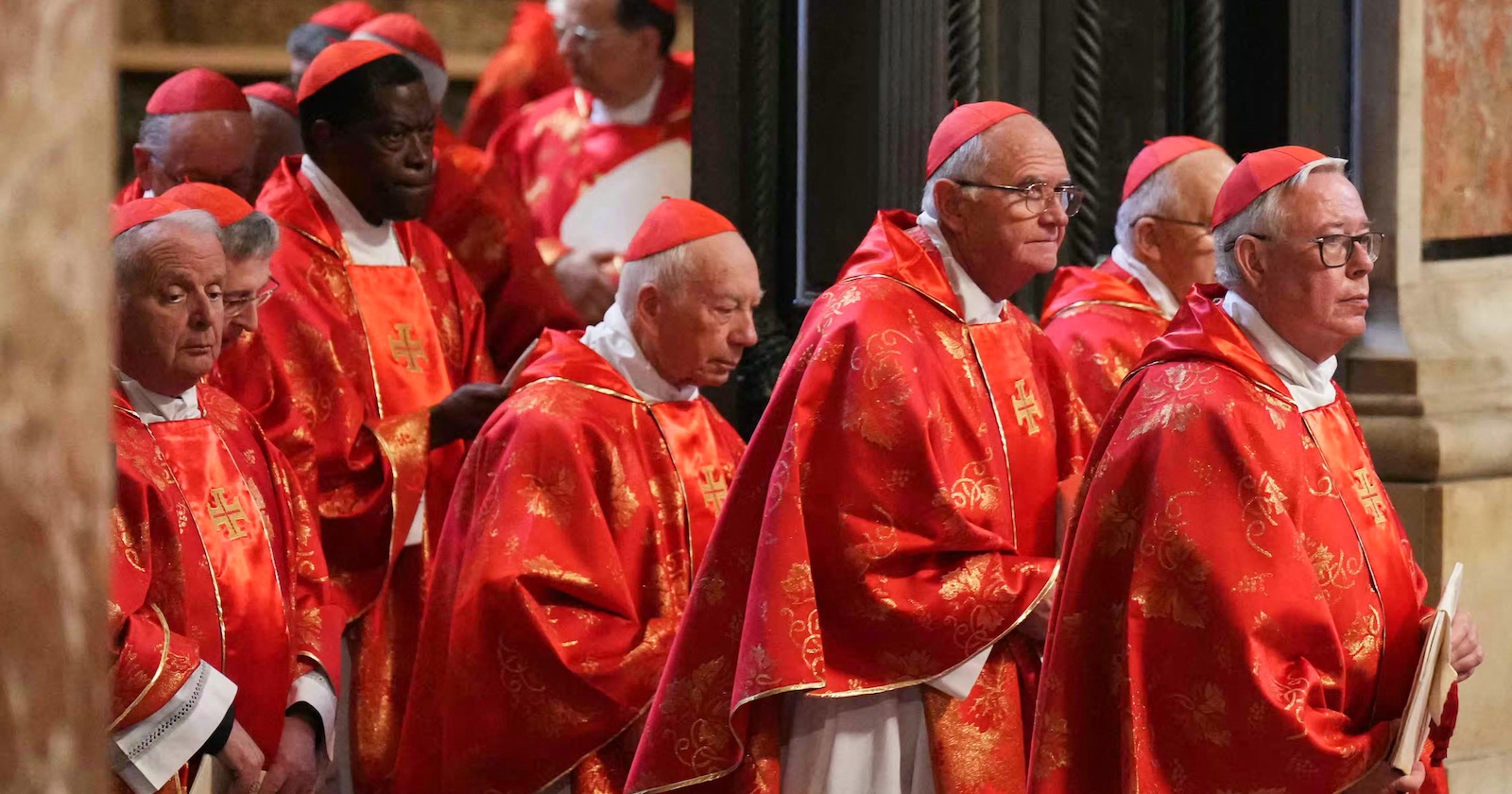 Mehrere Kardinäle in roten, reich verzierten Messgewändern stehen dicht beieinander in einer Kirche, vermutlich der Sixtinischen Kapelle, während des Konklaves zur Wahl eines neuen Papstes.