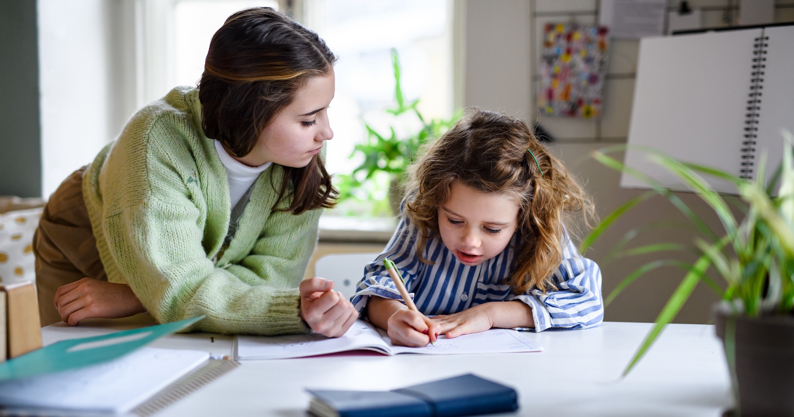 Ein Teenager hilft einem kleinen Mädchen beim Lernen.