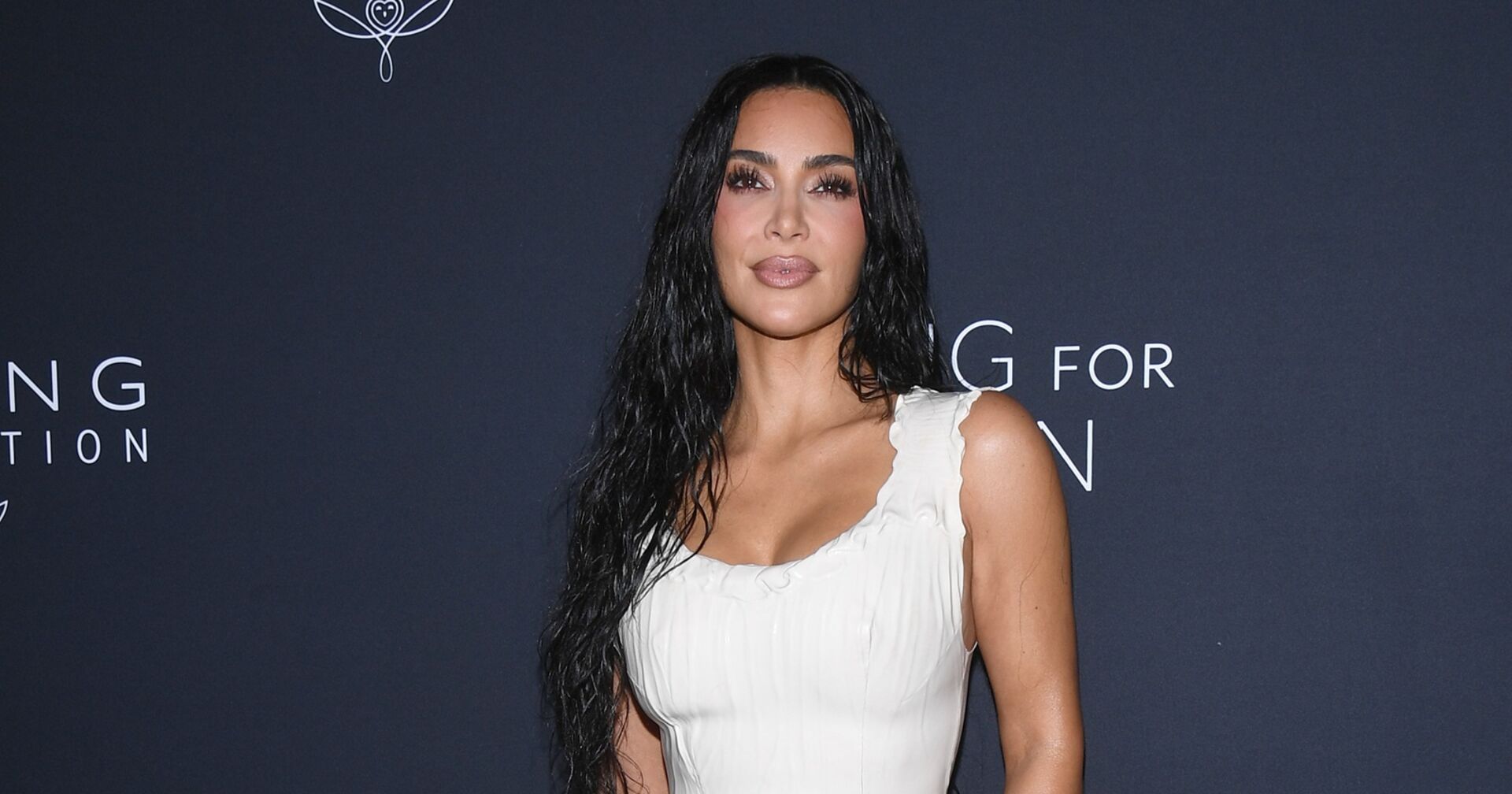 Medien-Persönlichkeit Kim Kardashian im weißen Kleid vor dunkelblauer Wand