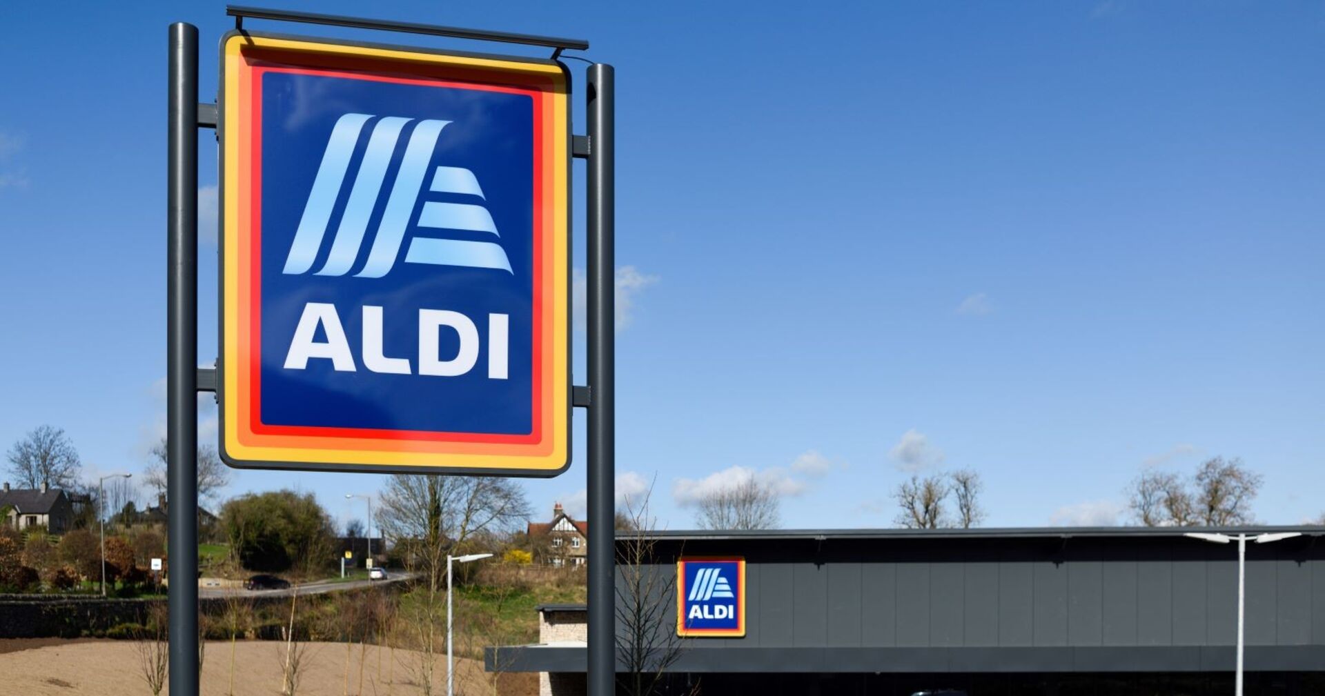 Aldi-Logo auf einem großen Schild vor einer Filiale bei blauem Himmel.