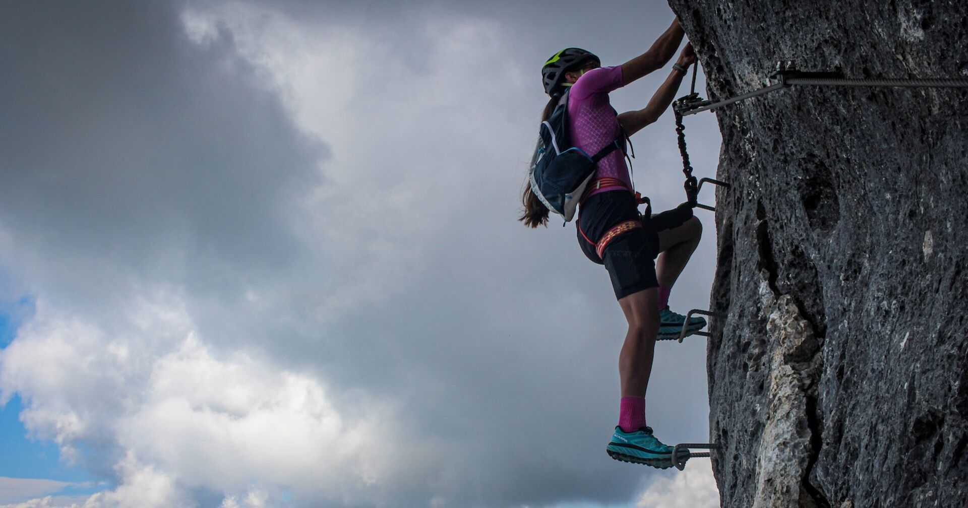 Eine Frau klettert auf einem Klettersteig.