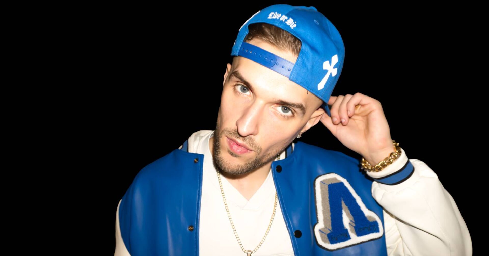 Porträt des Klagenfurter Rappers Gavis Dean, der eine blaue Baseball-Kappe sowie eine weiß-blaue Sportjacke trägt