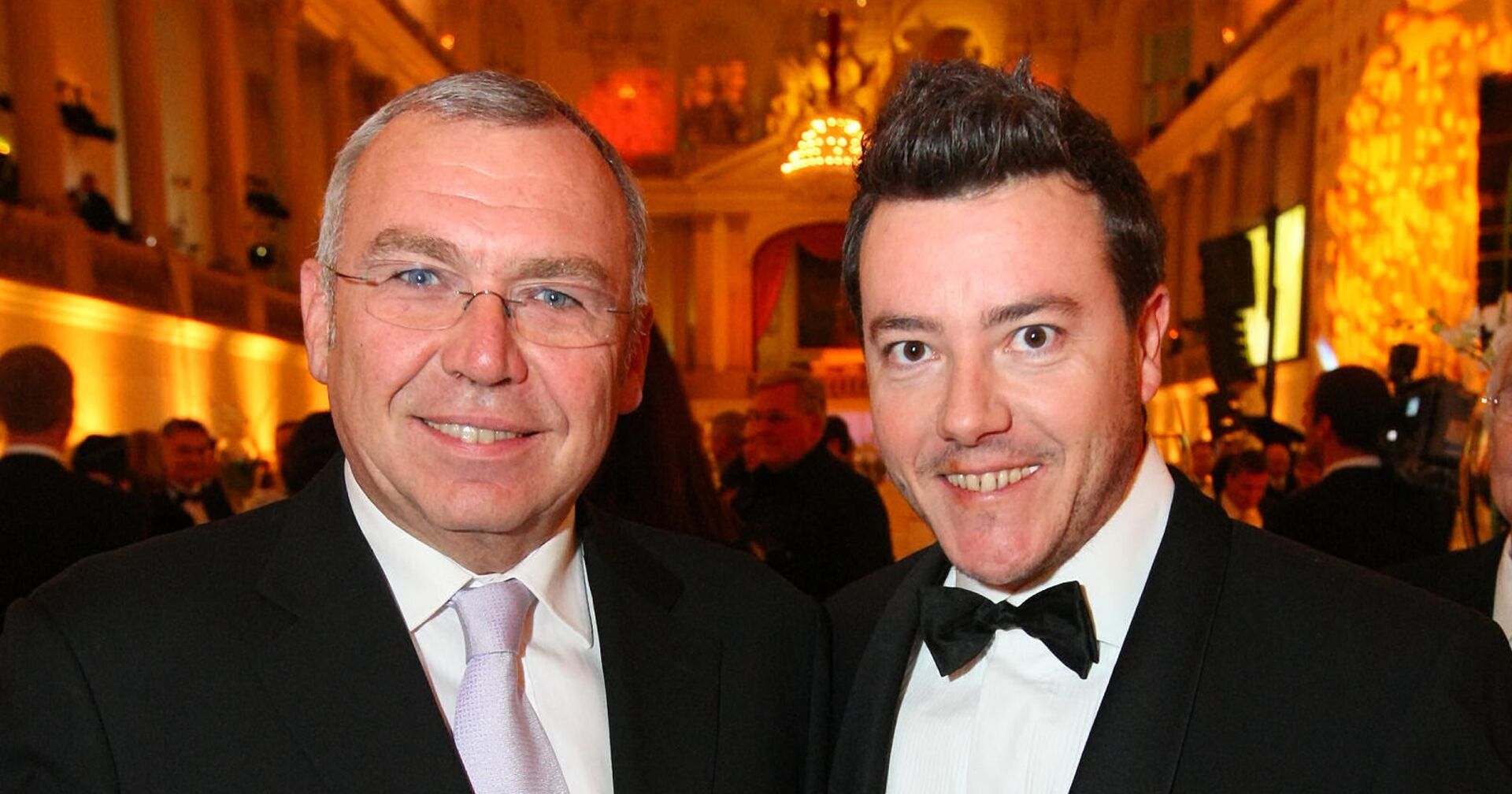 Ex-Kanzler Alfred Gusenbauer und Signa-Gründer René Benko lächelnd im Smoking bei einem Society-Event in Wien – heute verbindet sie vor allem ein milliardenschweres Insolvenzverfahren.