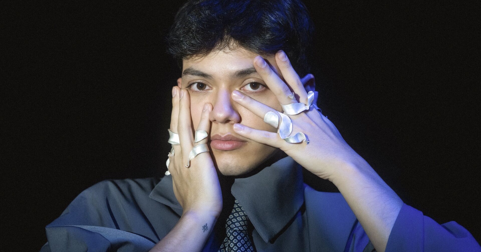 Sänger JJ hält die ringbesetzten Finger an seine Gesichtswangen