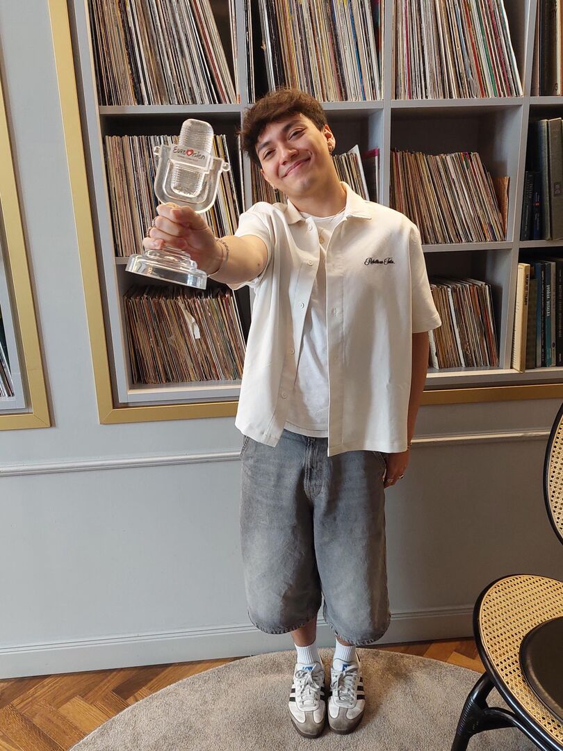 Sänger JJ mit Glasmikro vor einer Bücherwand