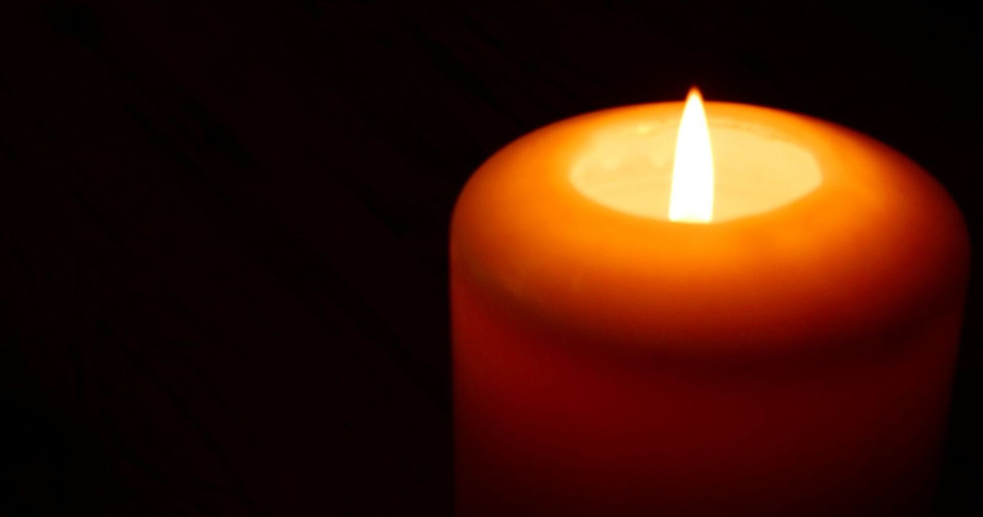 rote Kerze leuchtet vor schwarzem Hintergrund