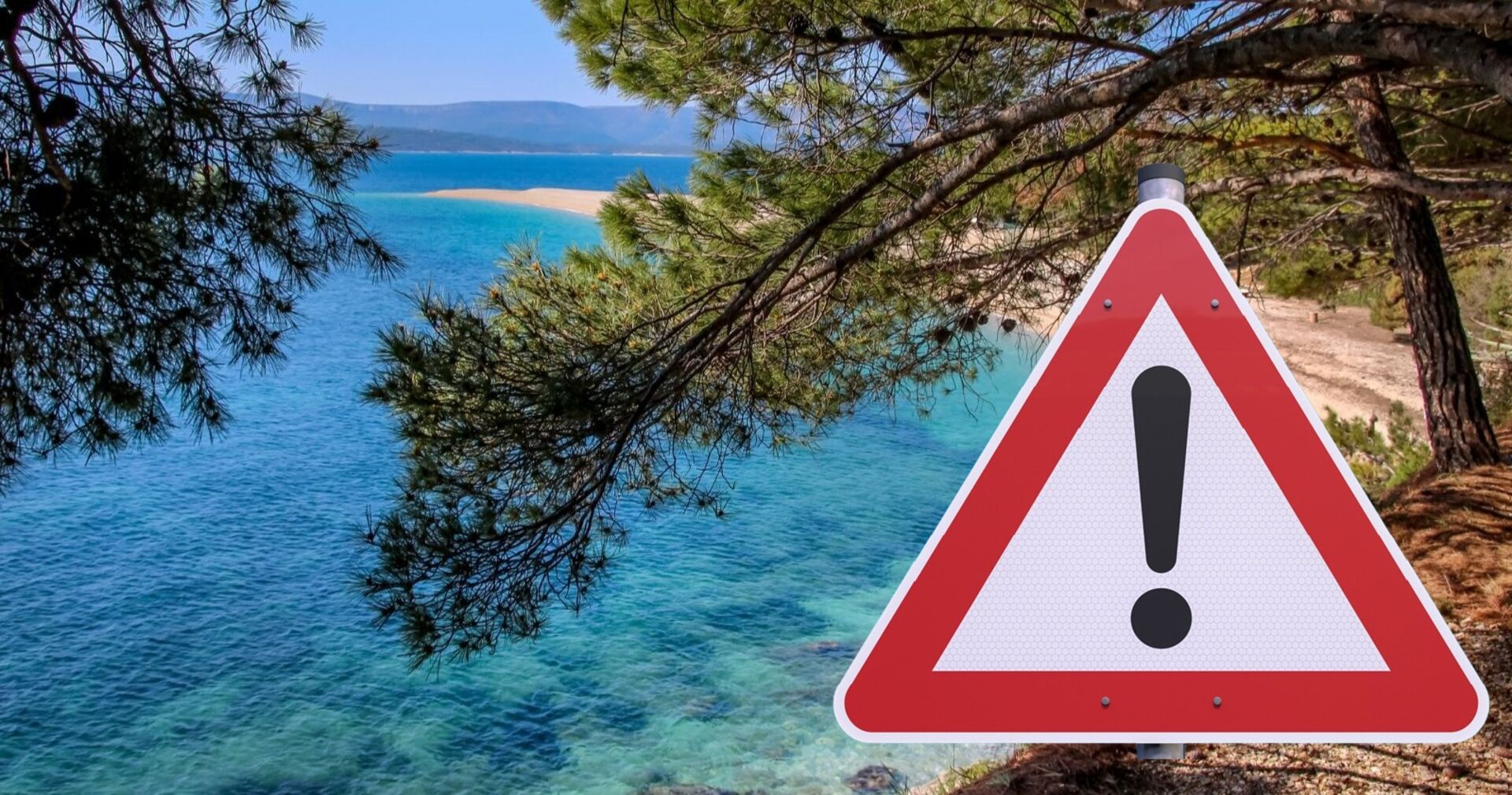Warnschild mit Ausrufezeichen vor türkisblauem Meer und Pinien in Kroatien – Symbol für aktuelle Reisewarnungen wegen Waldbränden und Verkehrschaos.