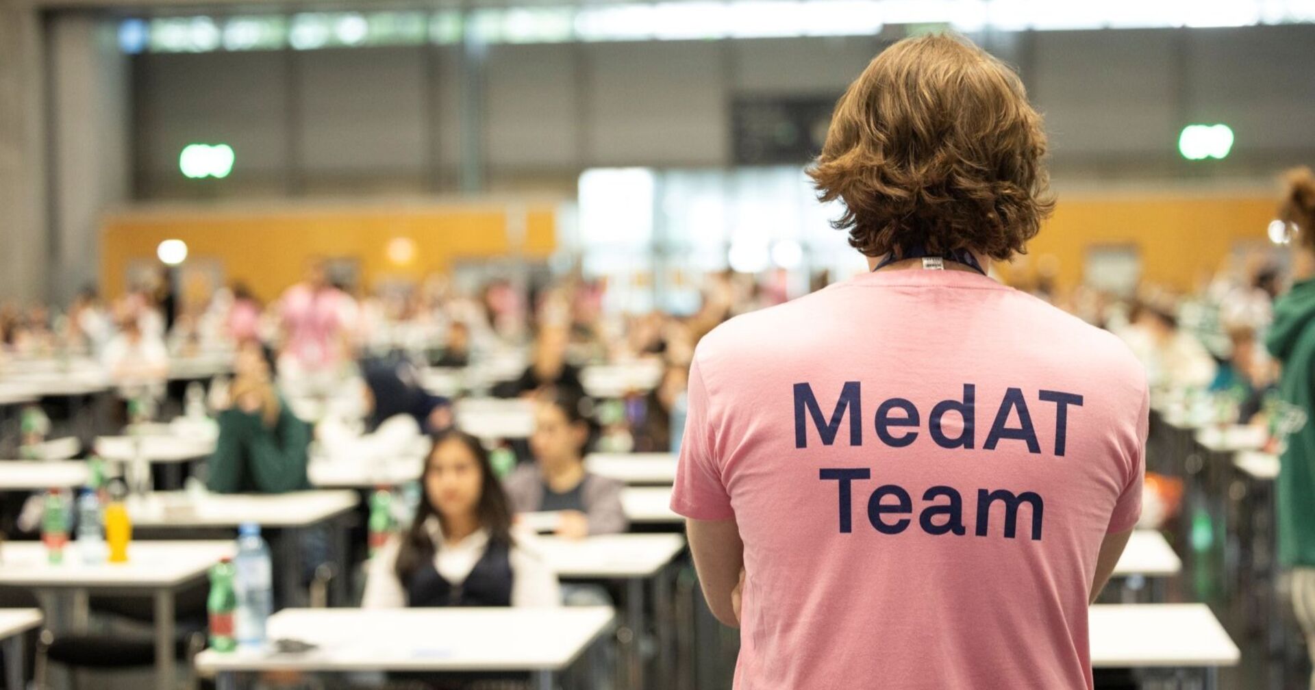 Mann steht in einem MedAT T-Shirt