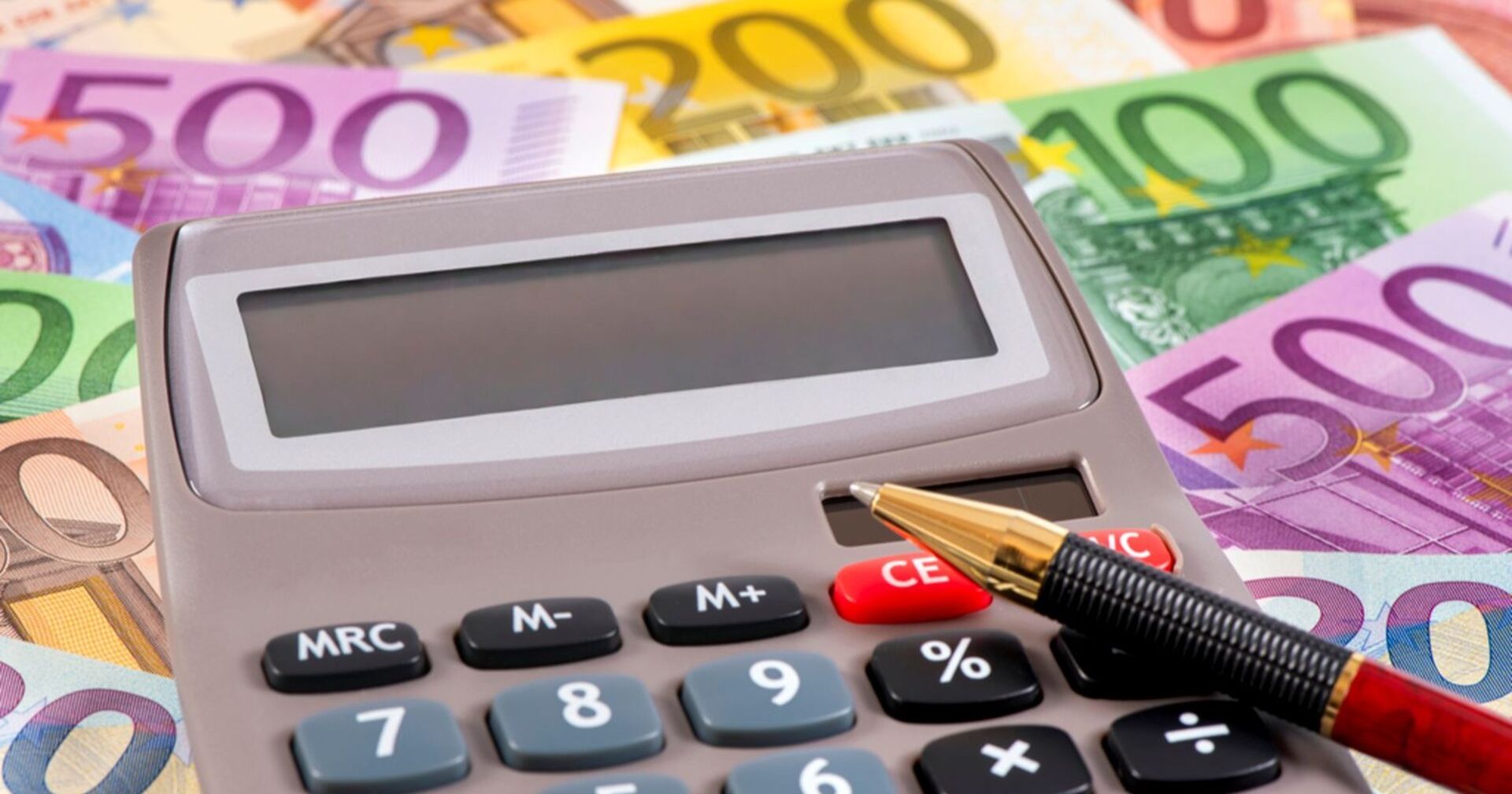 Taschenrechner auf dem ein Stift liegt gebettet auf Eurobanknoten
