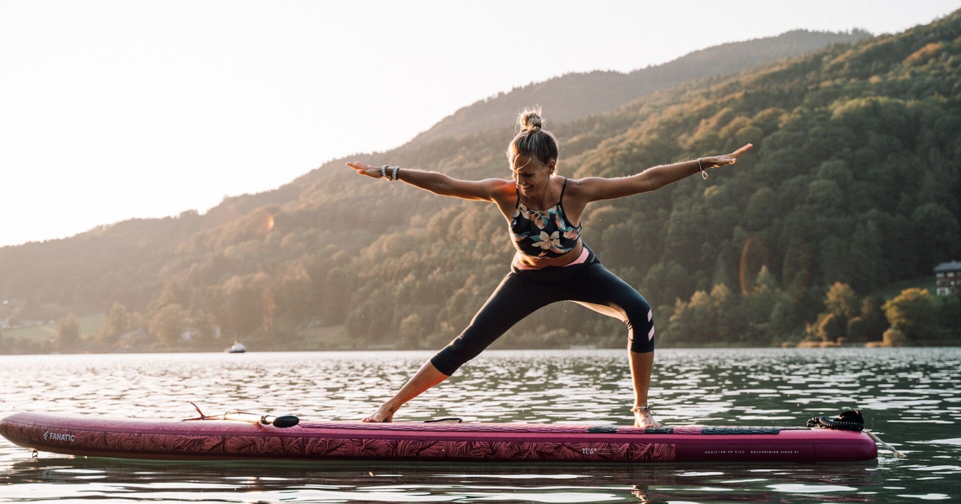 Eine Frau macht Yoga auf einem SUP auf dem Wasser.