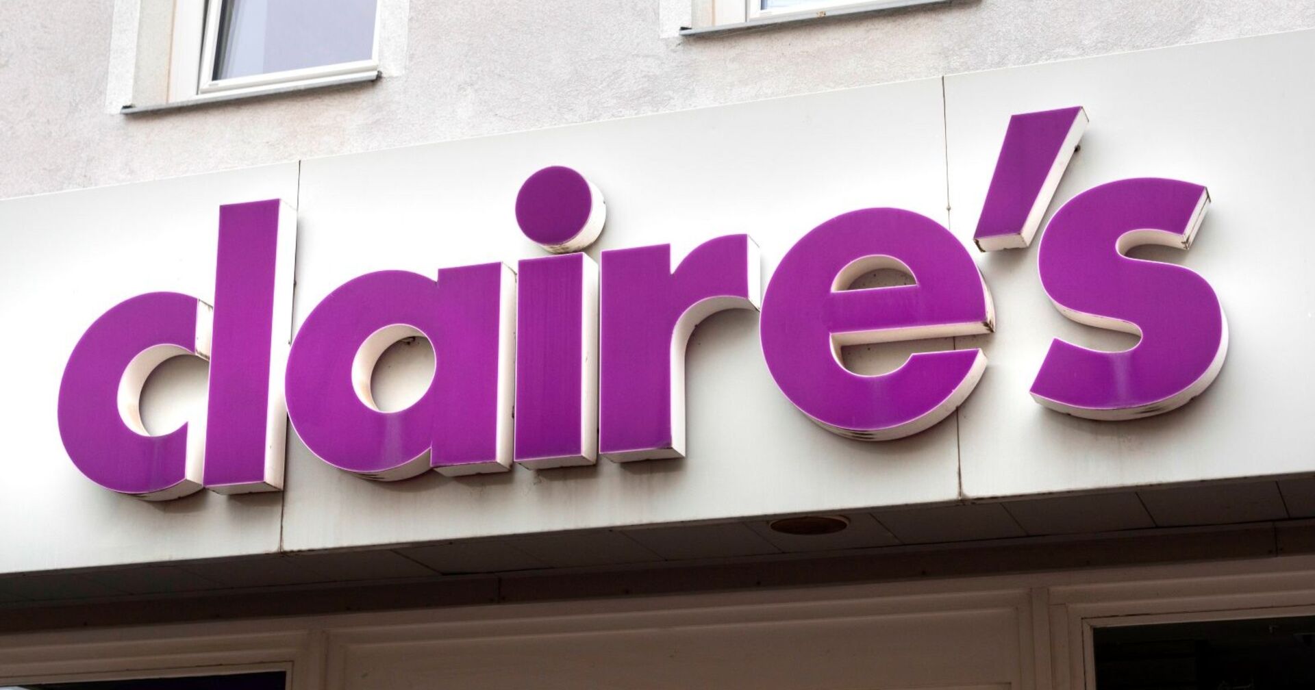 Violett-weißes Claire’s-Firmenschild an der Fassade eines Geschäftsgebäudes, Nahaufnahme der Ladenaufschrift.