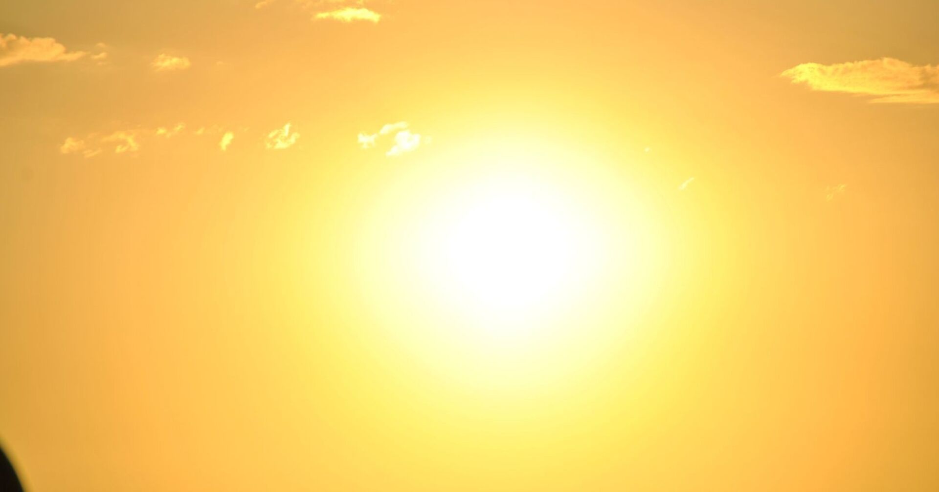 Grell strahlende Sonne am wolkenarmen Himmel, die intensive Hitze und sonniges Wetter andeutet.