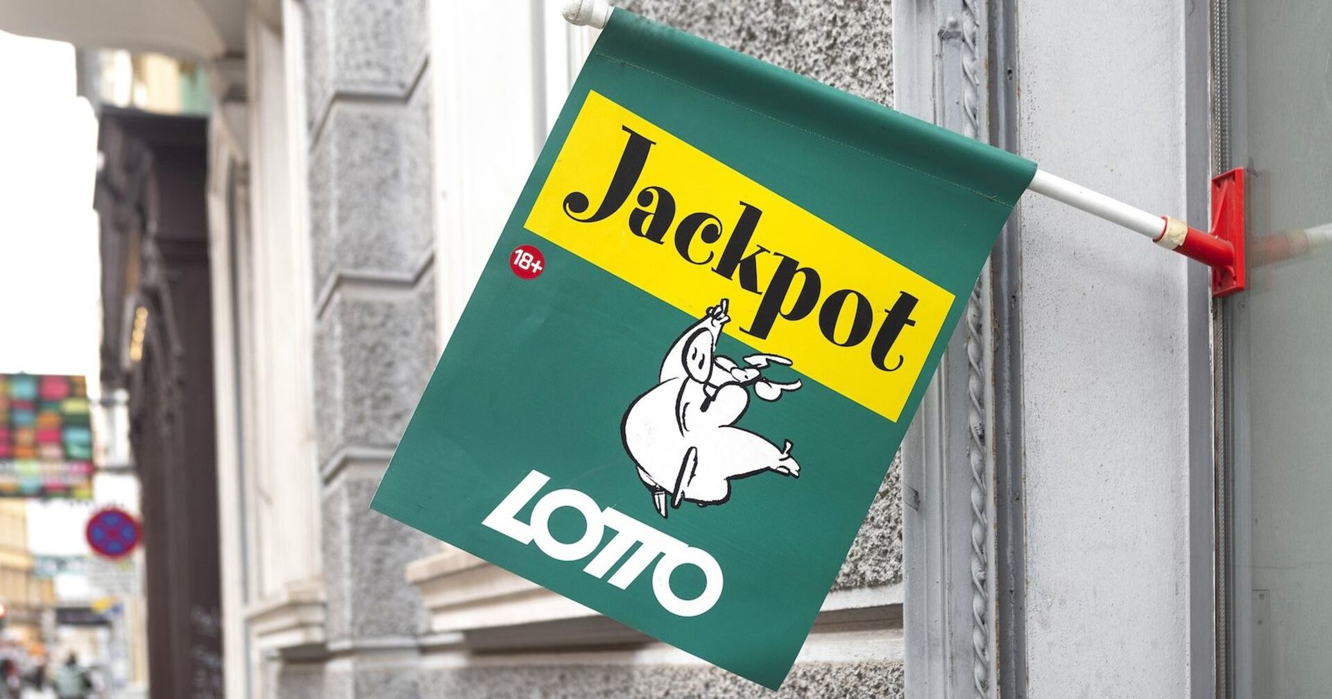 Grune Lotto-Fahne vor einer Trafik mit dem Lotto-Schwein als Markenzeichen