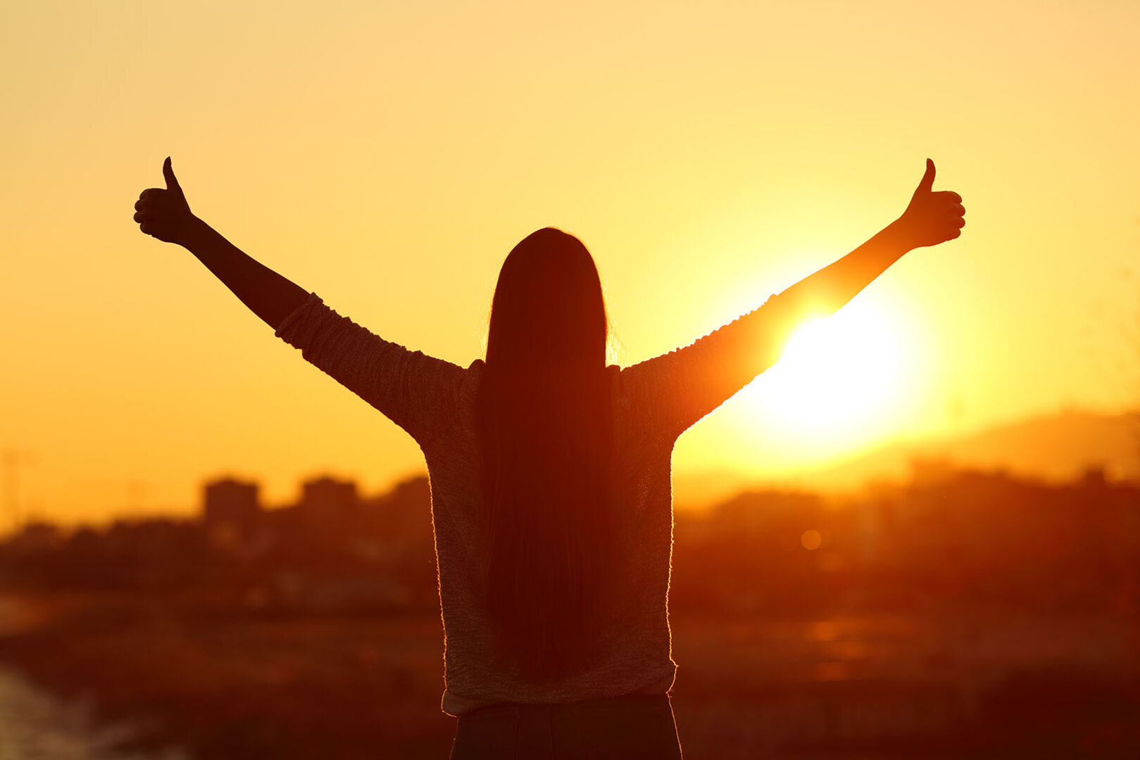 Frau steht im Sonnenaufgang | Credit: iStock.com/AntonioGuillem
