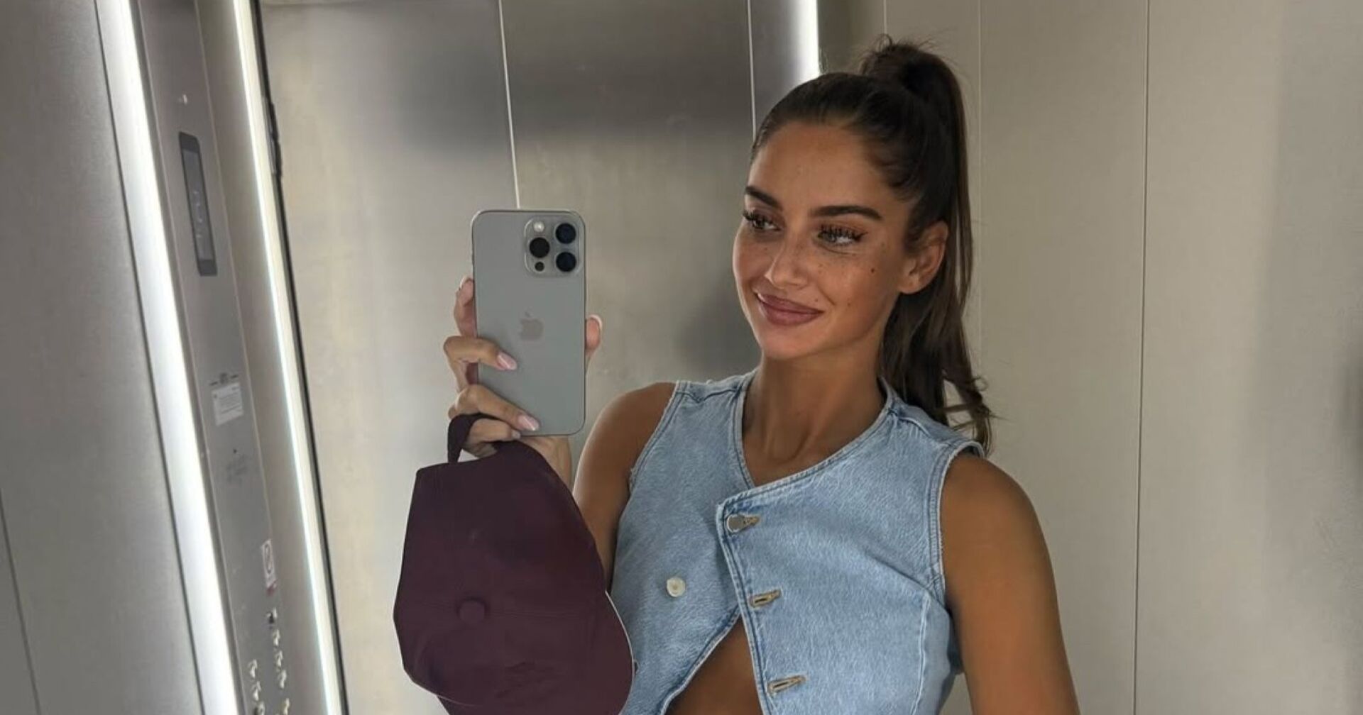 Tanja Makaric posiert in einem Aufzug und zeigt ihren Babybauch, in der Hand hält sie eine Kappe