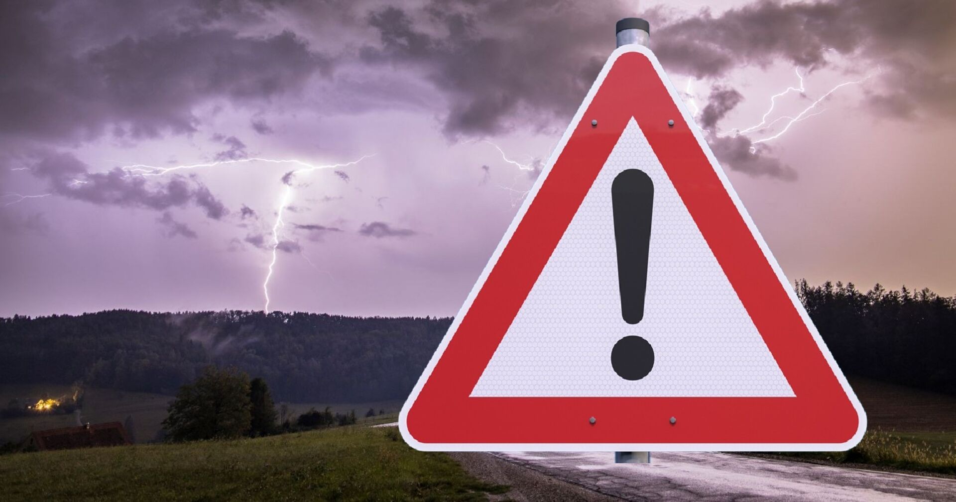 Warnschild mit Ausrufezeichen vor Gewitterhimmel mit Blitzen über einer ländlichen Landschaft.