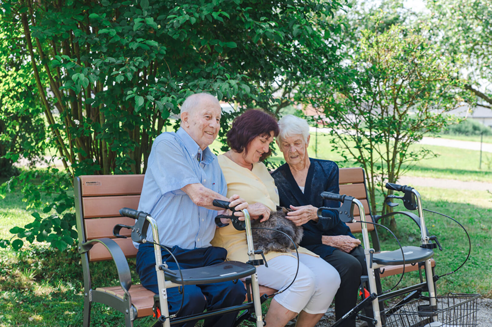 Weibliche Pflegekraft mit einer Seniorin und einem Senior auf der Parkbank | Credit: FraGes Holding/Johanna Gerner