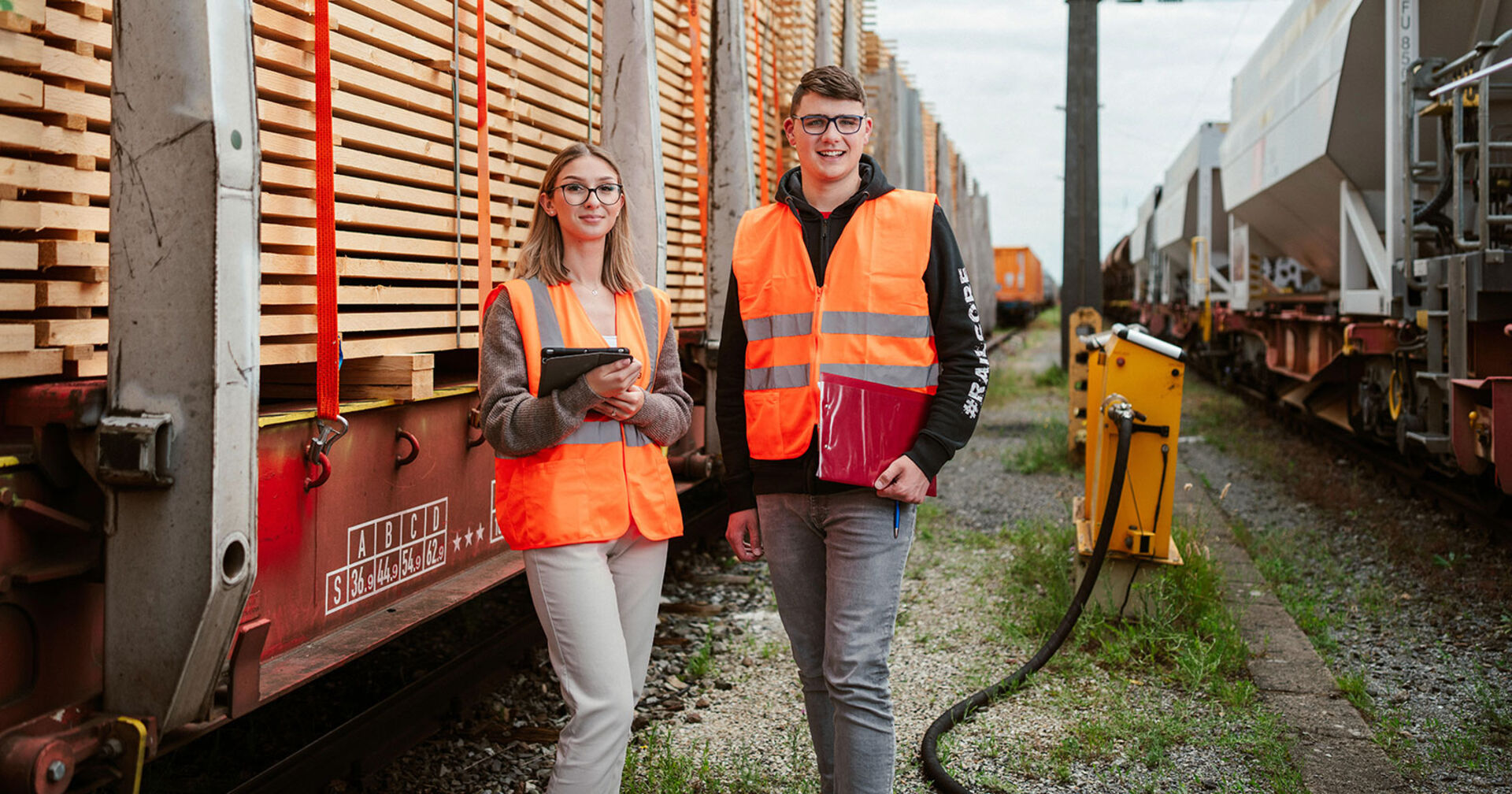Junge Frau und junger Mann in Arbeitskleidung neben einem Güterzug | Credit: ÖBB/Lukas Leonte