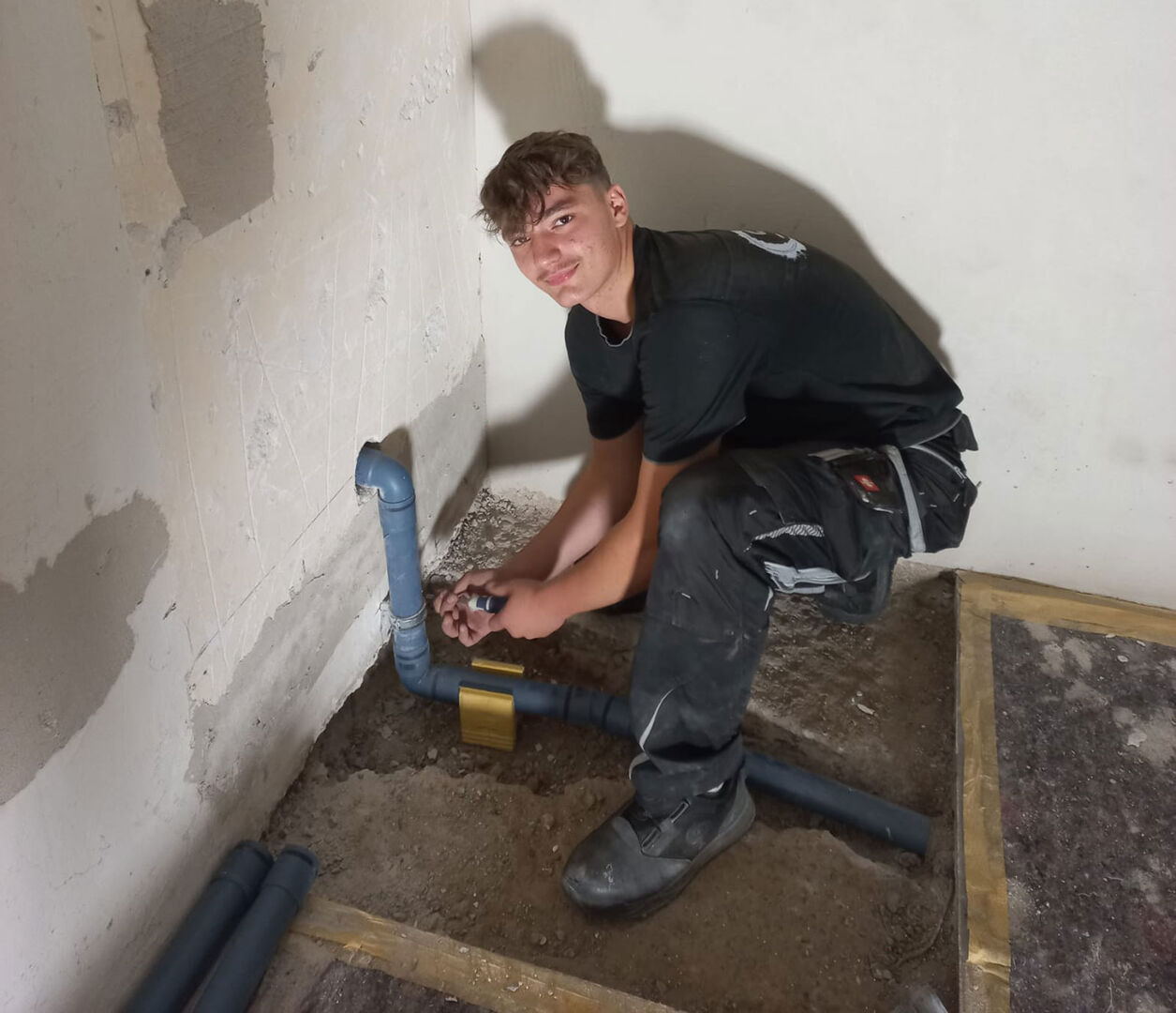 Junger Installateur beim Verlegen von Leitungen | Credit: Schick Gebäudetechnik