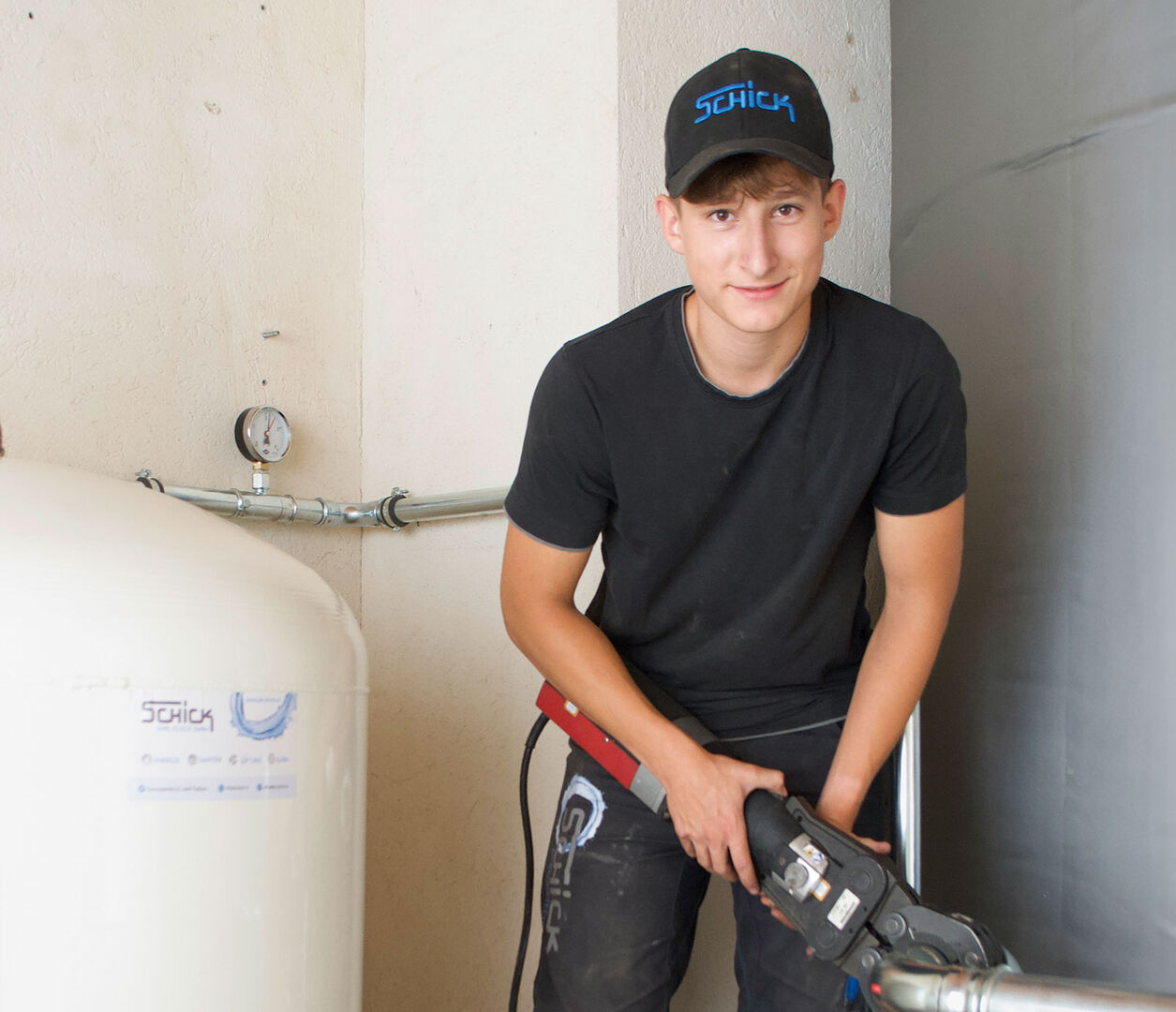 Junger Installateur beim Fixieren von Rohren | Credit: Schick Gebäudetechnik