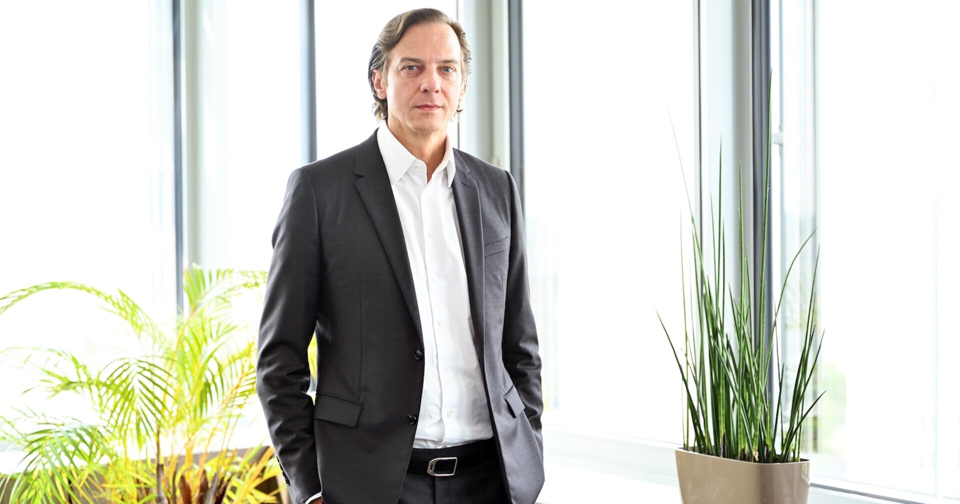 Porträt vor Fenster mit Händen in Hosentaschen