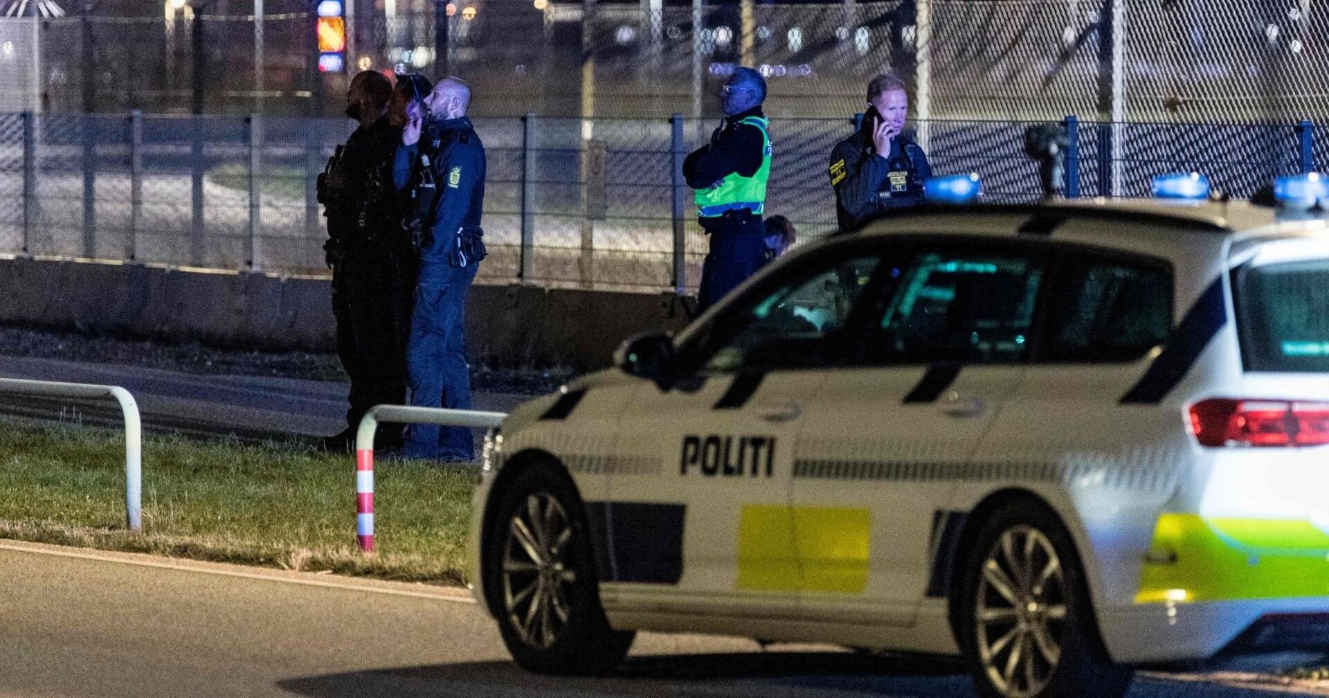 Mehrere Polizisten und ein Einsatzfahrzeug der dänischen Polizei vor einem abgesperrten Bereich am Flughafen Kopenhagen in der Nacht.