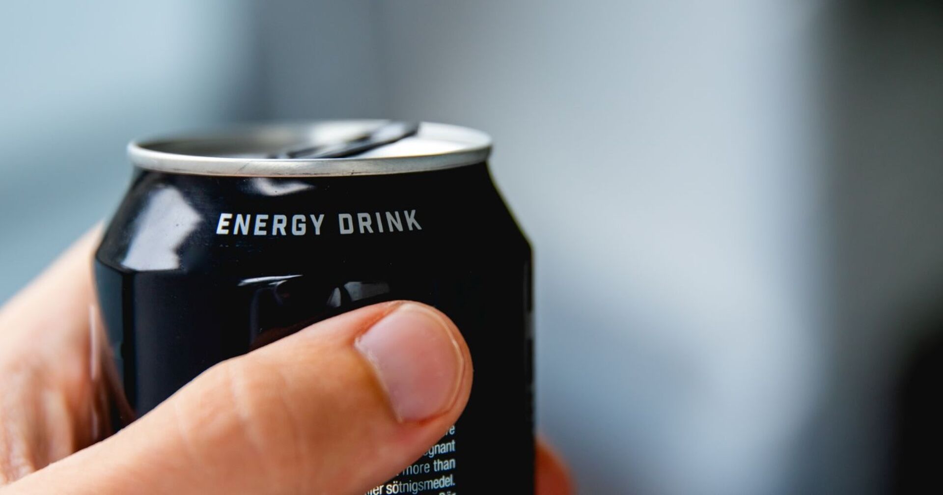Nahaufnahme einer menschlichen Hand, die eine Dose Energydrink hält