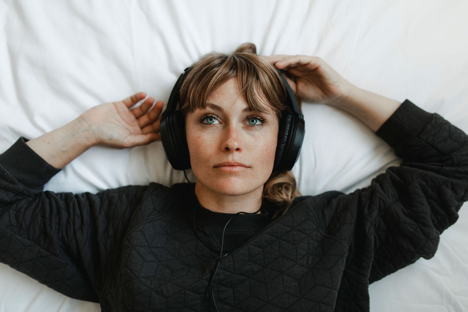 Frau liegt mit Kopfhörern im Bett | Credit: iStock.com/Rawpixel